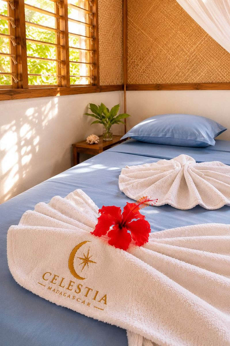 Le lit préparé avec les serviettes Celestia et une fleur d’hibiscus