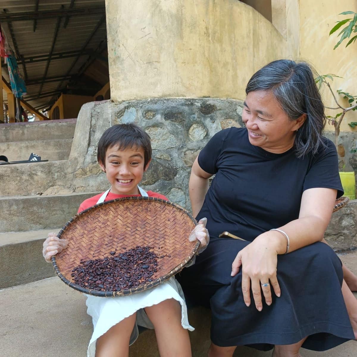 Un enfant tient un van de fèves de cacao