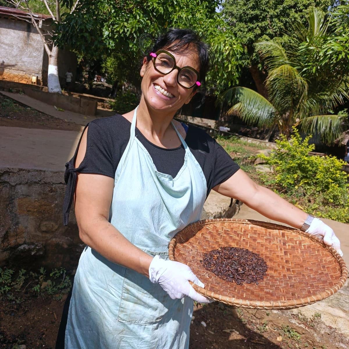 Une participante souriante tient un van de fèves de cacao