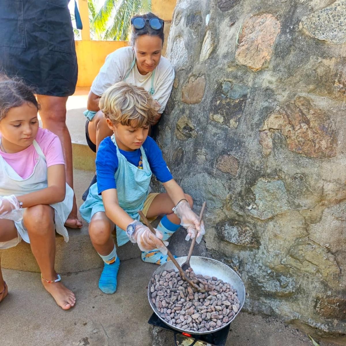 Des enfants remuent les fèves pendant la torréfaction